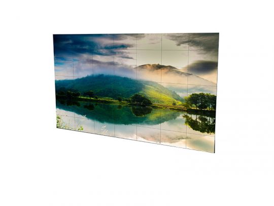 Steglose Videowand 7x7 aus 55-Zoll-Displays zur Miete, zeigt eine beeindruckende Landschaft mit grünen Hügeln, einem ruhigen See und Sonnenstrahlen, die durch einen teils bewölkten Himmel brechen.