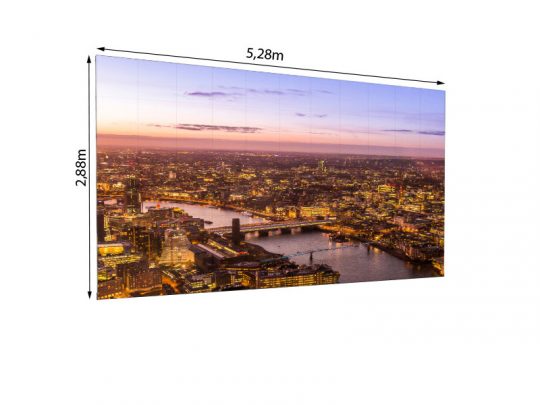 LEDitgo sB2HB LED Wand 5.28m x 2.88m (2,5mm Pixelpitch) mieten - großes Display zeigt farbintensives Luftbild einer City-Skyline mit Fluss und beleuchteten Hochhäusern bei Sonnenuntergang; professionelle LED-Videowand, ideal für Events und Präsentationen. SEO-Hinweis: Produktname ("LEDitgo sB2HB LED Wand mieten"), Maße und Haupteinsatz werden genannt; Bildmotiv (Stadt, Fluss, Beleuchtung, Event-Wirkung) wird präzise beschrieben.