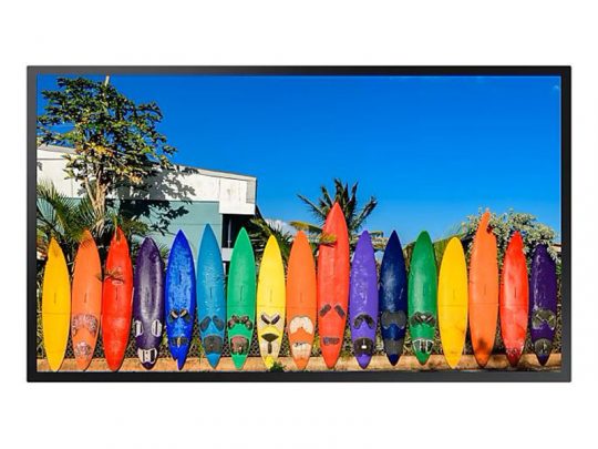 Mehrere bunte Surfboards stehen vertikal nebeneinander an einer Außenwand; im Hintergrund sind grüne Pflanzen und blauer Himmel zu sehen. Ideal als Miet- oder Kauf-Surfboards für deinen nächsten Strandurlaub.