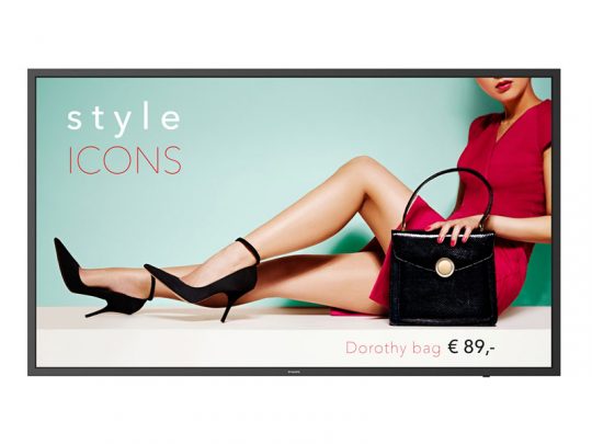 Eine Frau trägt ein elegantes rotes Kleid und schwarze High Heels und hält die schwarze Dorothy Bag in der Hand. Neben ihr steht der Schriftzug "style ICONS und Dorothy Bag: mieten oder kaufen ab €89,-" vor einem hellblauen und beigen Hintergrund. Die Szene vermittelt stilvolle Mode-Inspiration zum Mieten oder Kaufen der Designer-Handtasche.