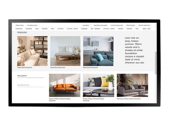 Auf dem Bildschirm eines Computers ist eine moderne Möbel-Website zu sehen, die verschiedene stilvolle Sofas in Wohnzimmer-Umgebungen präsentiert. Rechts neben den Bildern befindet sich ein Textfeld mit Informationen über entspannte, sommerliche Einrichtungsideen sowie Schaltflächen zum Kaufen oder Mieten der Lieblingsmöbel.