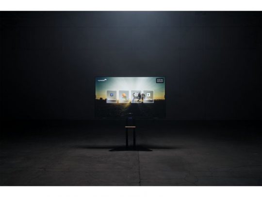 55 Zoll Touchdisplay Legamaster EVOLVE 2 ETX-5540 (Neuware) steht auf einem kleinen Tisch in einem dunklen Raum mit Betonboden - das moderne, rahmenlose Display eignet sich perfekt als Home-Entertainment-Lösung oder für Präsentationen.