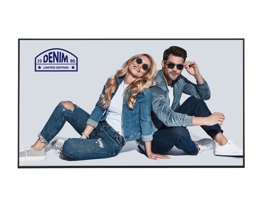 Zwei Personen, eine Frau und ein Mann, tragen lässige Denim-Outfits und Sonnenbrillen. Sie sitzen nebeneinander auf dem Boden und posieren modern für die Kamera. Im linken oberen Bildbereich ist das Denim Limited Edition Logo zu sehen.
