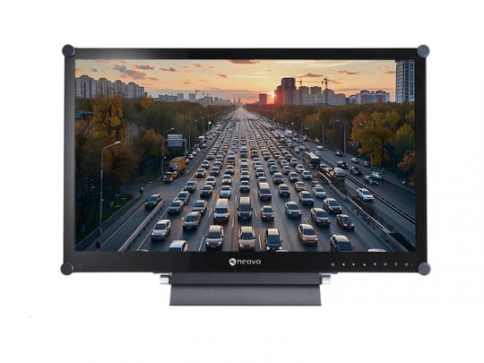Computer-Monitor "Model X27" zeigt ein Bild einer belebten Stadtautobahn bei Sonnenuntergang, auf der viele Autos fahren; auf beiden Seiten der Straße stehen Bäume und Gebäude.