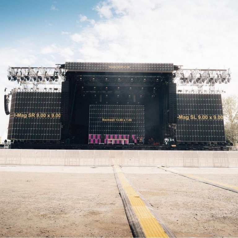 LED Wand mieten: Große Outdoor-Bühne mit schwarzen LED-Wänden, leerem abgesperrtem Bereich und gelbem Kabelschutz am Boden.